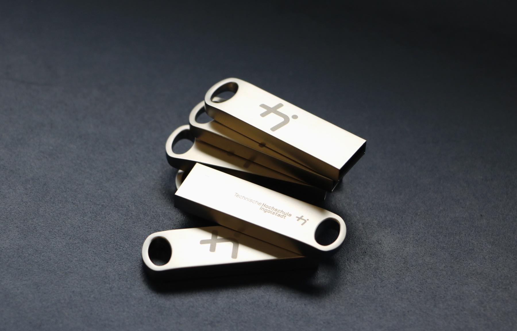 A stack of metal USB sticks with THI embossing